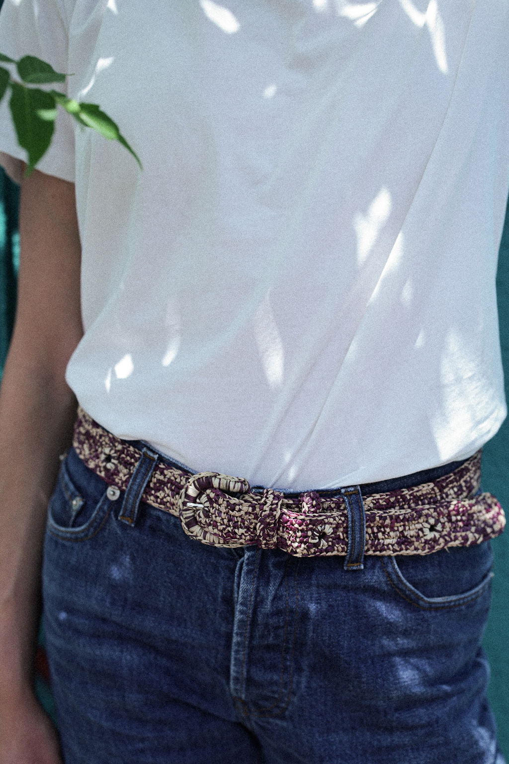 zoom sur la ceinture à boucle en raphia chinée naturel et bordeaux sur un jean 
