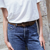 zoom sur la ceinture à boucle en raphia marron tabac portée sur un jean brut