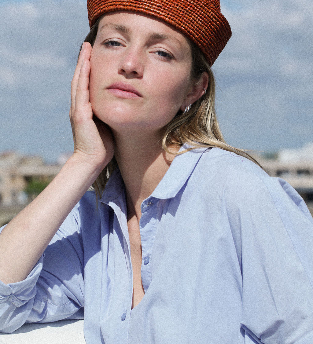 vue de face du petit chapeau en raphia terracotta porté avec une chemise bleue
