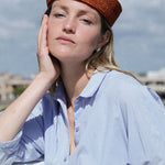vue de face du petit chapeau en raphia terracotta porté avec une chemise bleue