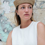 chapeau de marin en raphia marron clair porté sur une robe blanche