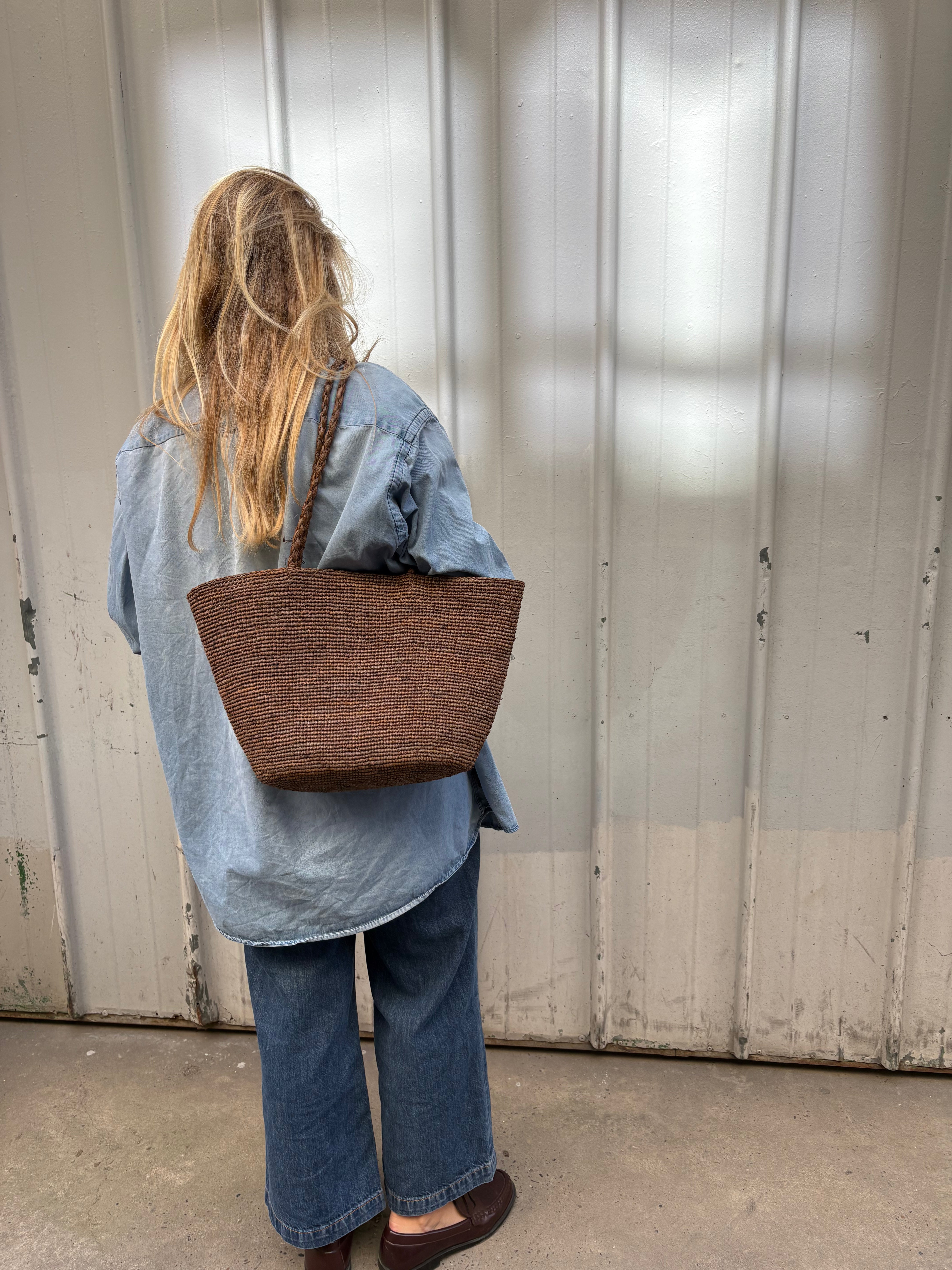 grand cabas en crochet de raphia marron porté avec une tenue décontractée