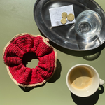 grand chouchou en raphia rouge posé sur la table d'un café