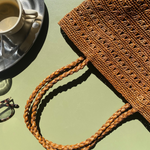 petit cabas marron en raphia ajouré posé à la terrasse d'un café