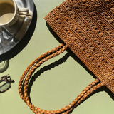 petit cabas marron en raphia ajouré posé à la terrasse d'un café