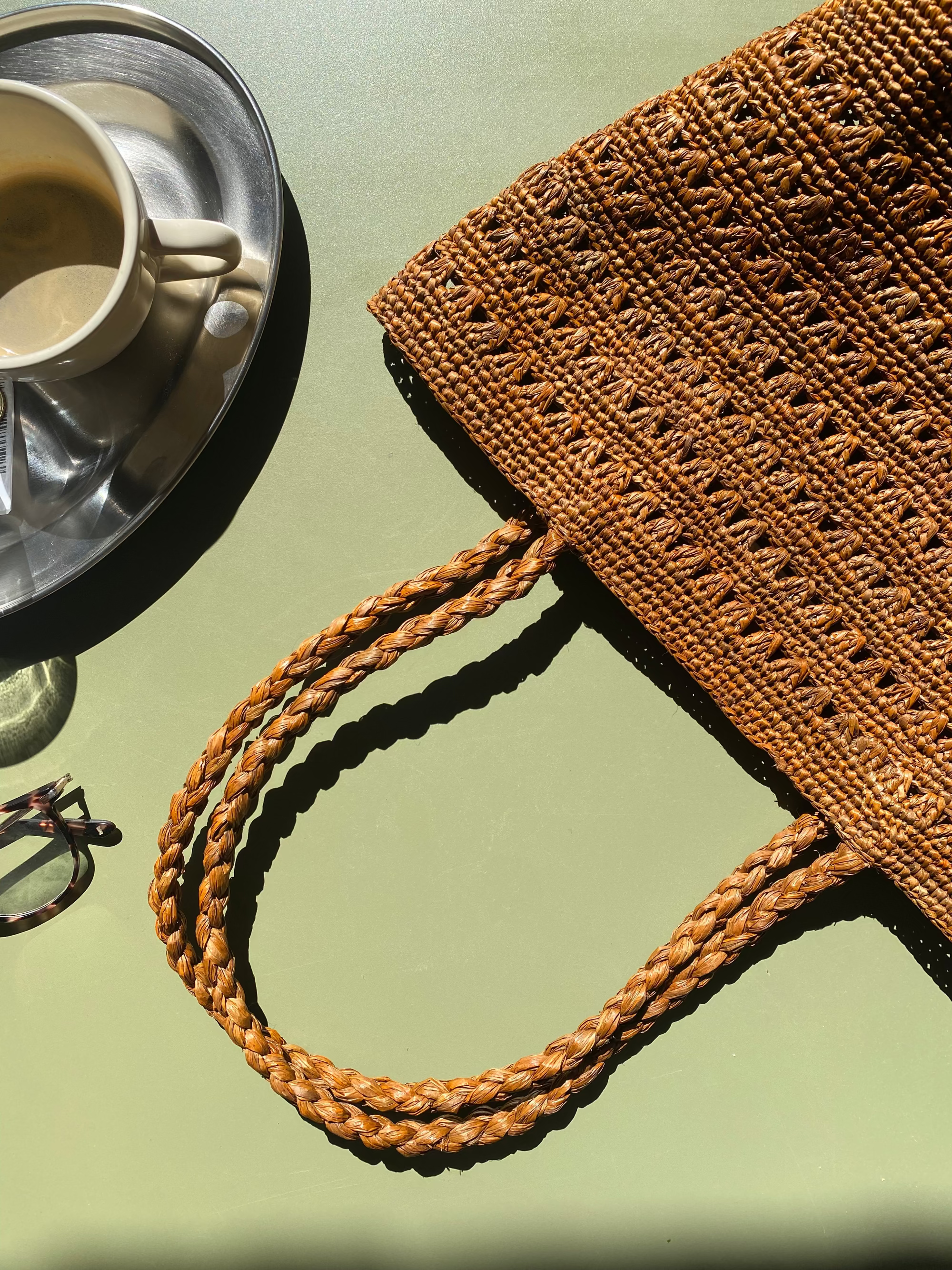 petit cabas marron en raphia ajouré posé à la terrasse d'un café
