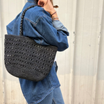 petit sac cabas ajouré en raphia noir porté à l'épaule 