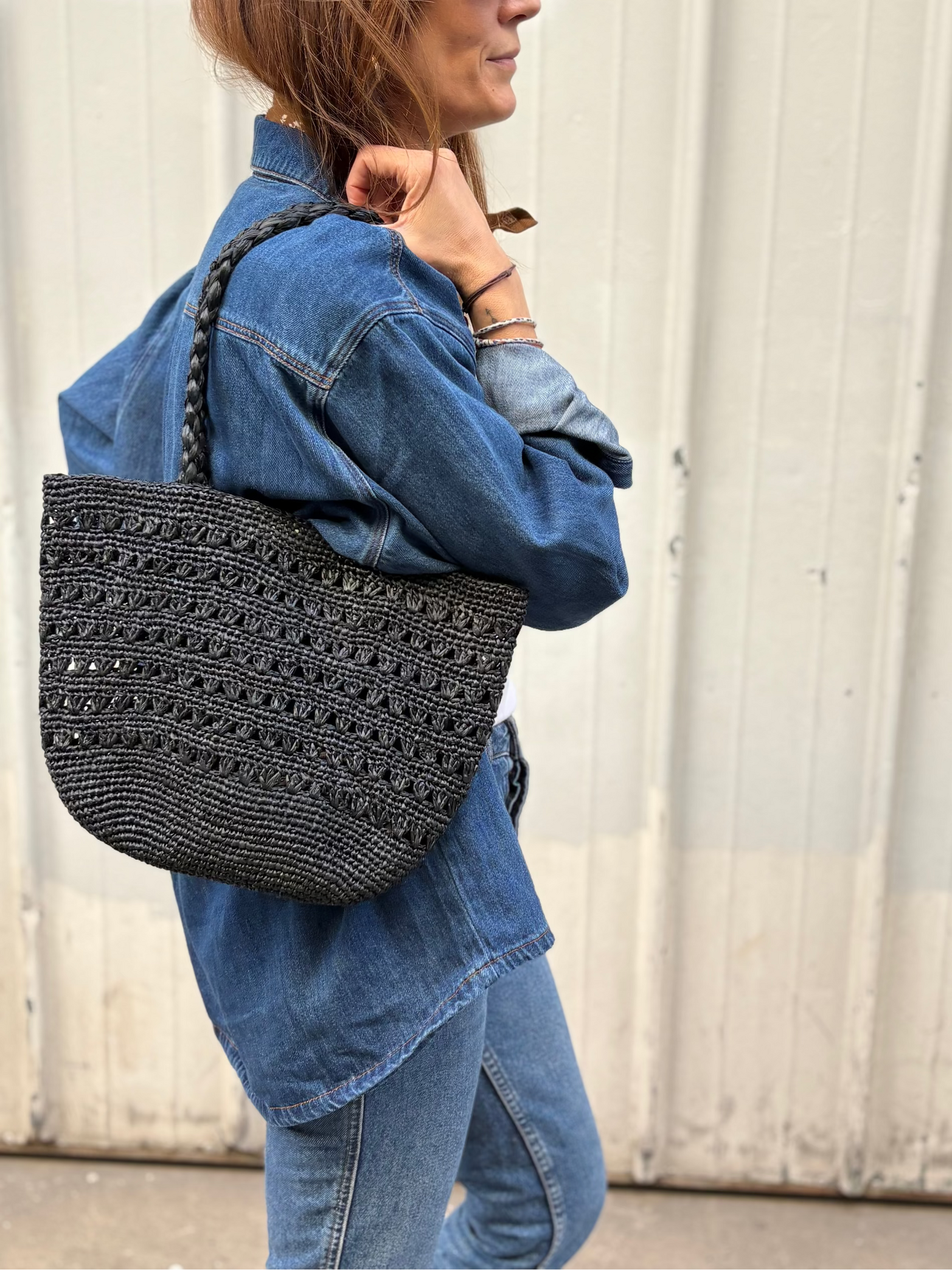 petit sac cabas ajouré en raphia noir porté à l'épaule 