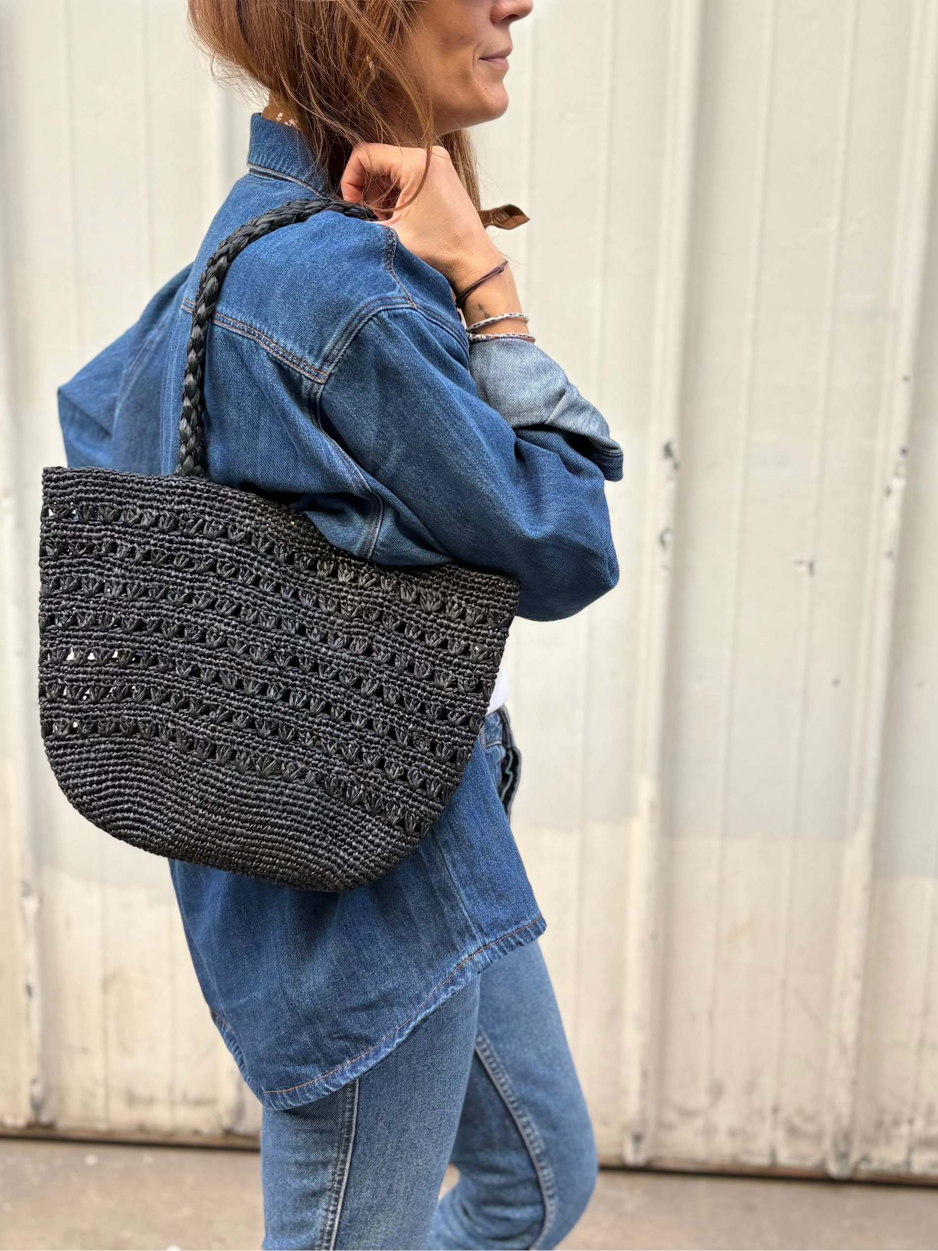 petit sac cabas ajouré en raphia noir porté à l'épaule 