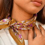 petit foulard en coton caramel aux motifs floraux violet et rose pâle noué au cou