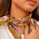 petit foulard en coton caramel aux motifs floraux violet et rose pâle noué au cou