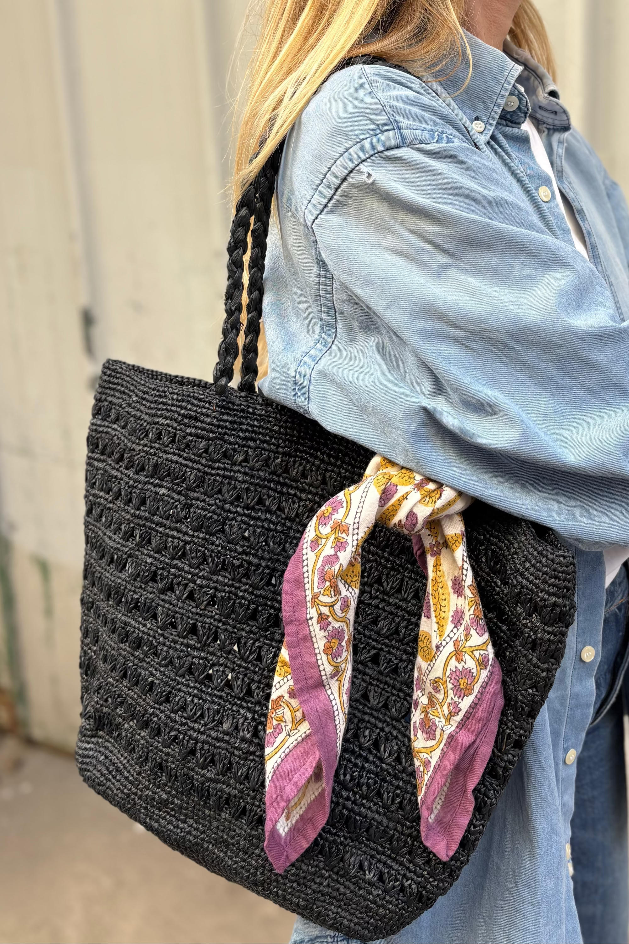 petit foulard en block print noué sur un sac en raphia noir 