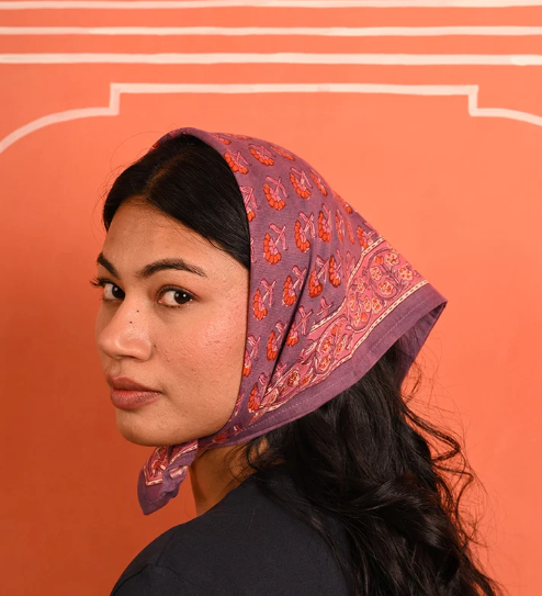 petit foulard en coton imprimé violet et rose noué sur la tête comme un fichu