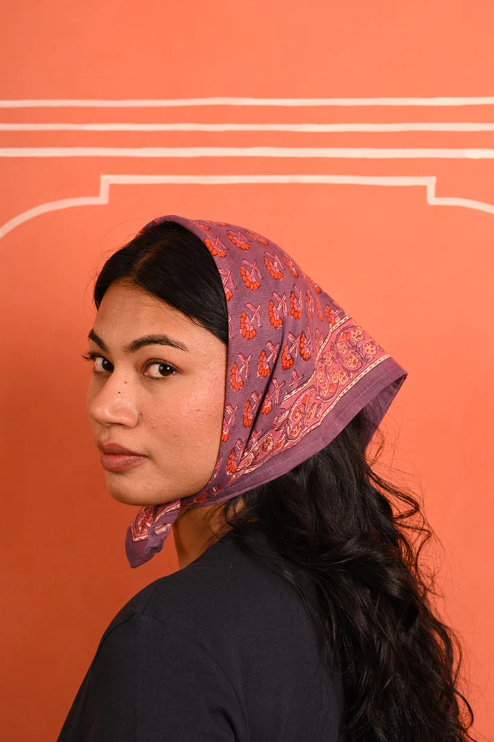 petit foulard en coton imprimé violet et rose noué sur la tête comme un fichu