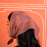 petit foulard en coton imprimé violet porté comme un fichu sur la tête
