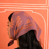 petit foulard en coton imprimé violet porté comme un fichu sur la tête