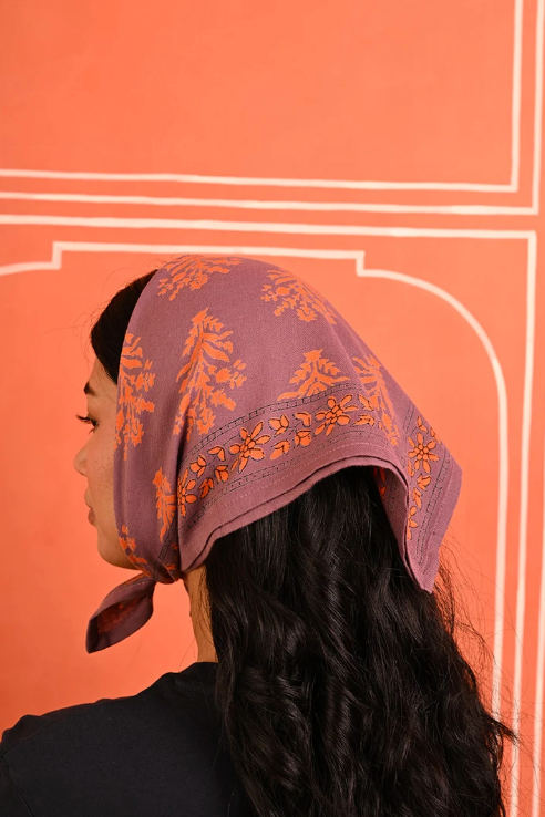 petit foulard en coton imprimé violet porté comme un fichu sur la tête