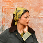 petit foulard vert olive en coton imprimé noué dans les cheveux comme un fichu