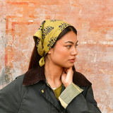 petit foulard vert olive en coton imprimé noué dans les cheveux comme un fichu