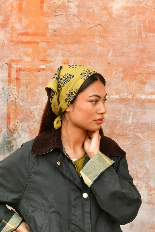 petit foulard vert olive en coton imprimé noué dans les cheveux comme un fichu