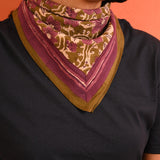 petit foulard en coton kaki avec motif floral violet porté comme un bandana