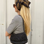 Petit sac en raphia noir porté à l’épaule, élégant et minimal