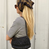 Petit sac en raphia noir porté à l’épaule, élégant et minimal
