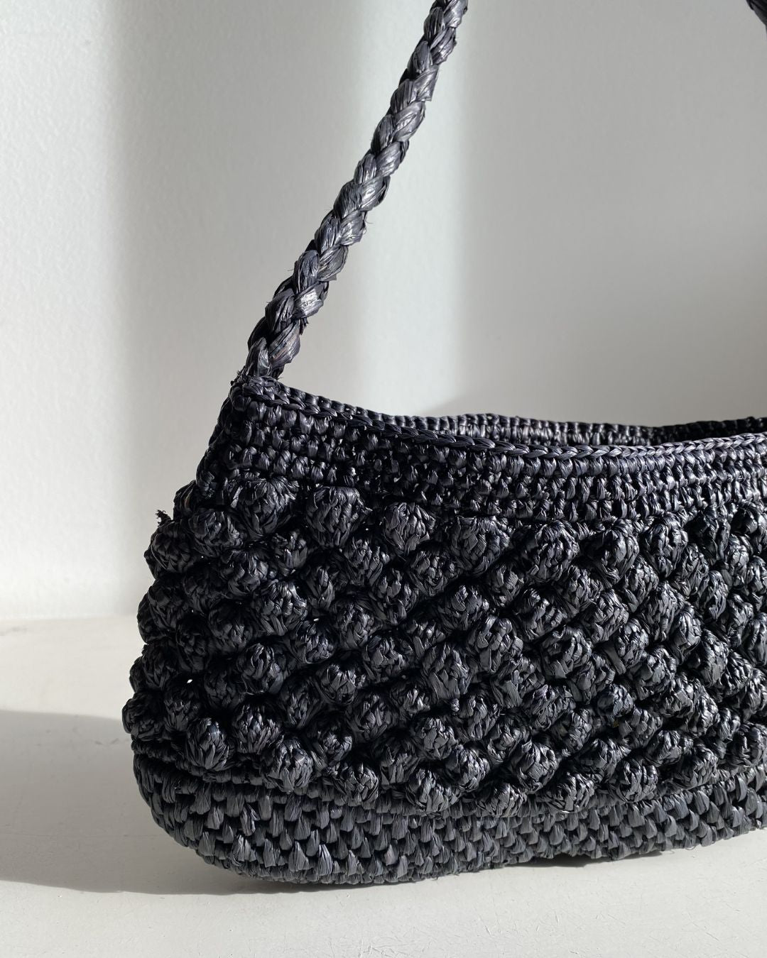 Petit sac en raphia noir vu de côté, format baguette structuré- BAO noir