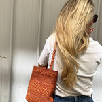 Petit sac en raphia rouille porté à l’épaule, léger et naturel