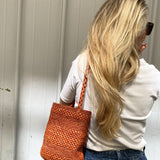 Petit sac en raphia rouille porté à l’épaule, léger et naturel