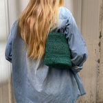 vue du dos du petit sac seau vert en raphia porté à l'épaule