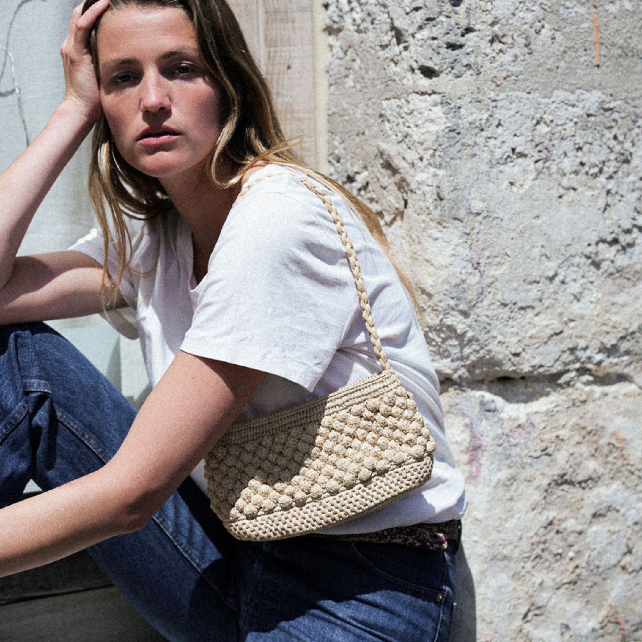 petit sac baguette naturel en raphia boules porté à l'épaule 