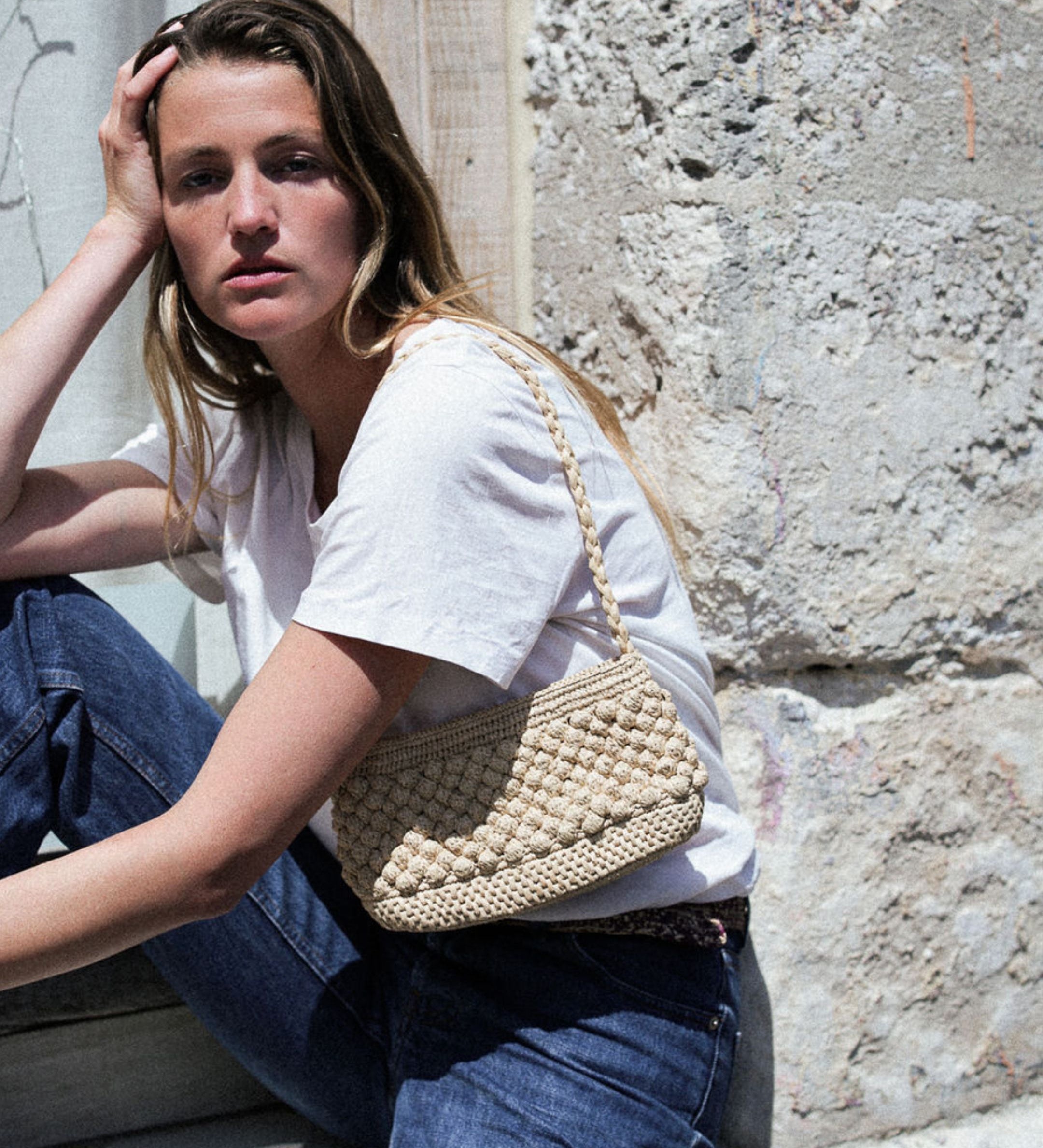 petit sac baguette naturel en raphia boules porté à l'épaule 