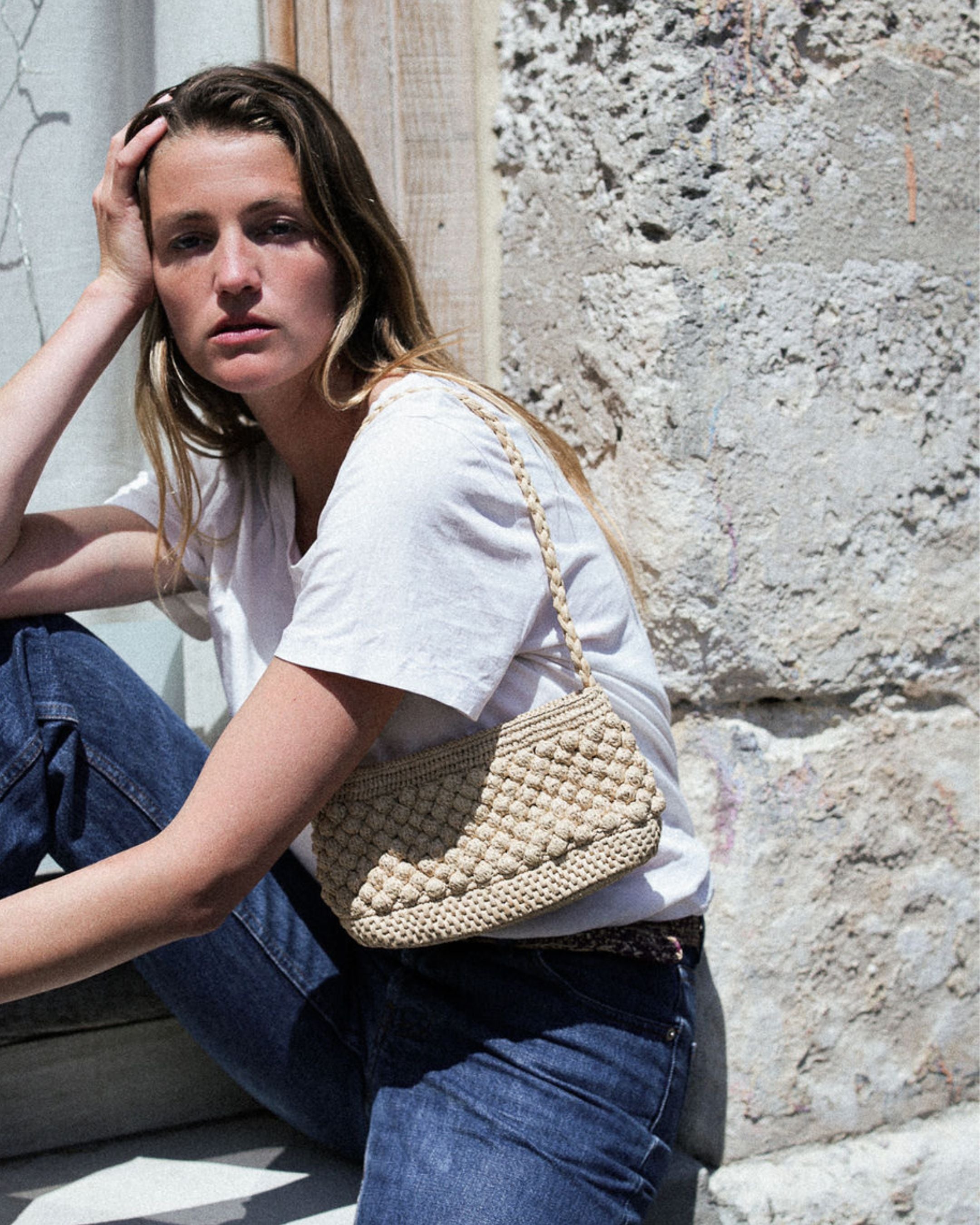 petit sac baguette naturel en raphia boules porté à l'épaule 