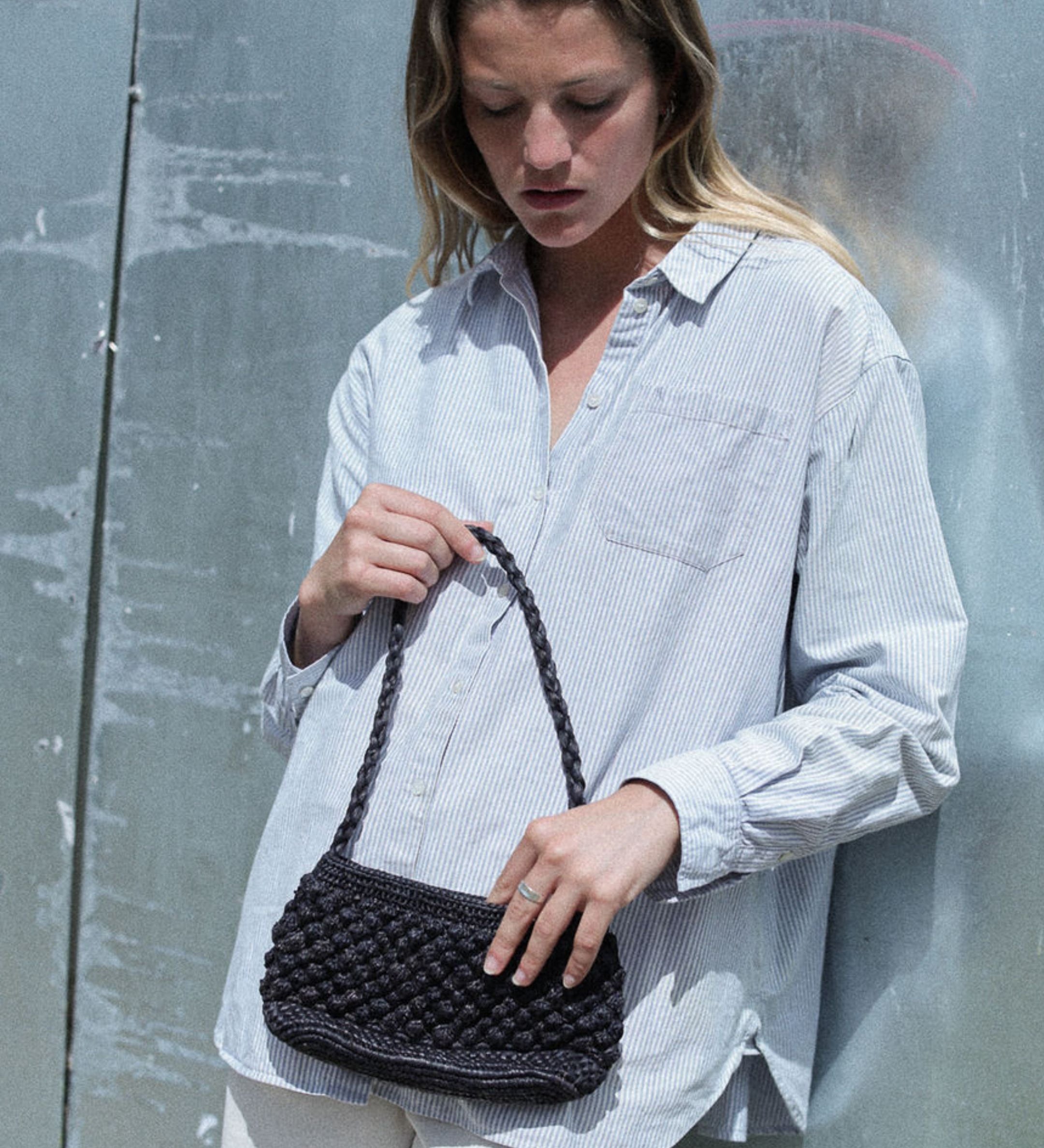 petit sac baguette noir en raphia boules porté avec une tenue de ville