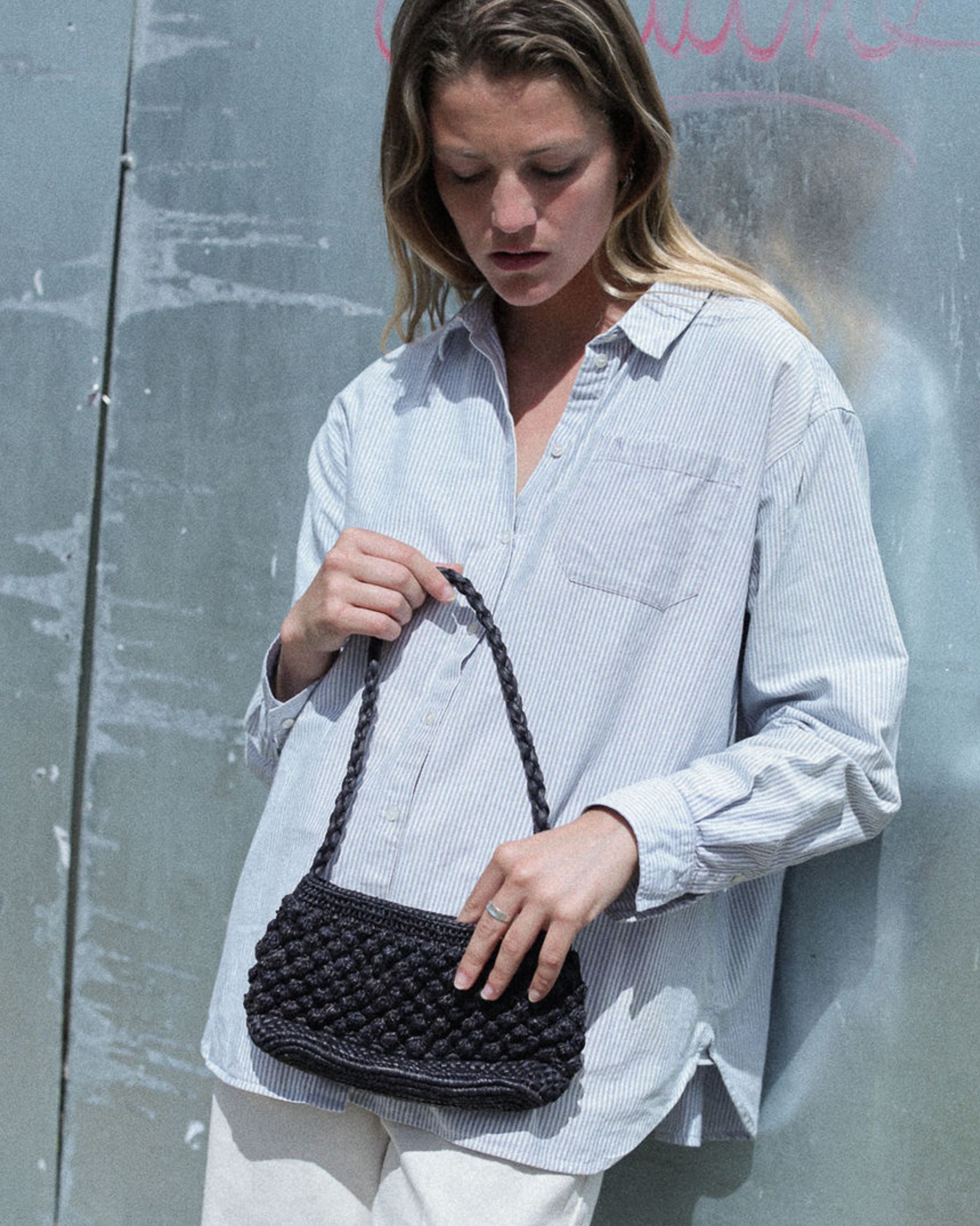 petit sac baguette noir en raphia boules porté avec une tenue de ville
