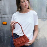 petit sac baguette terracotta en raphia boules porté sur un jean 