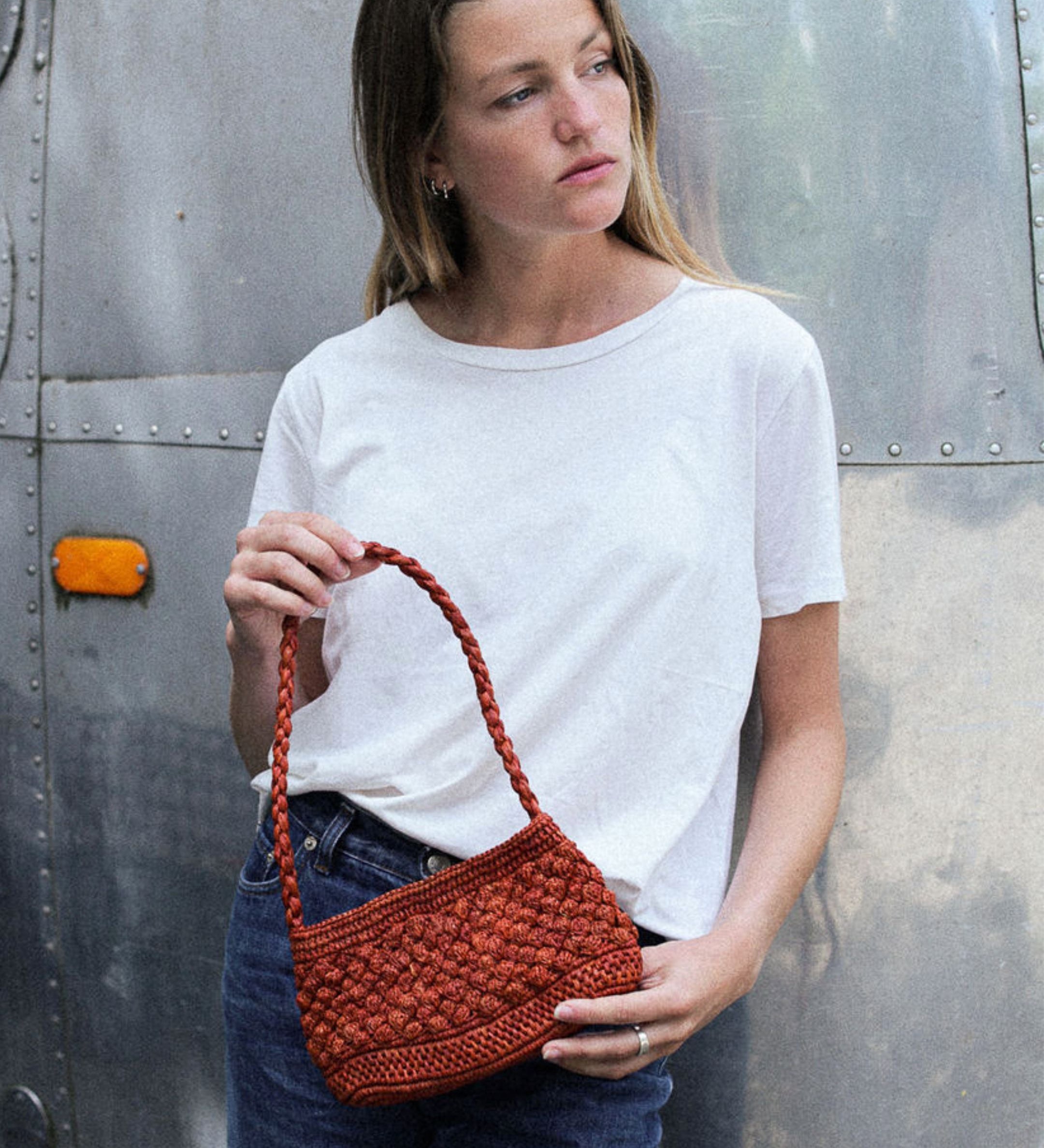 petit sac baguette terracotta en raphia boules porté sur un jean 