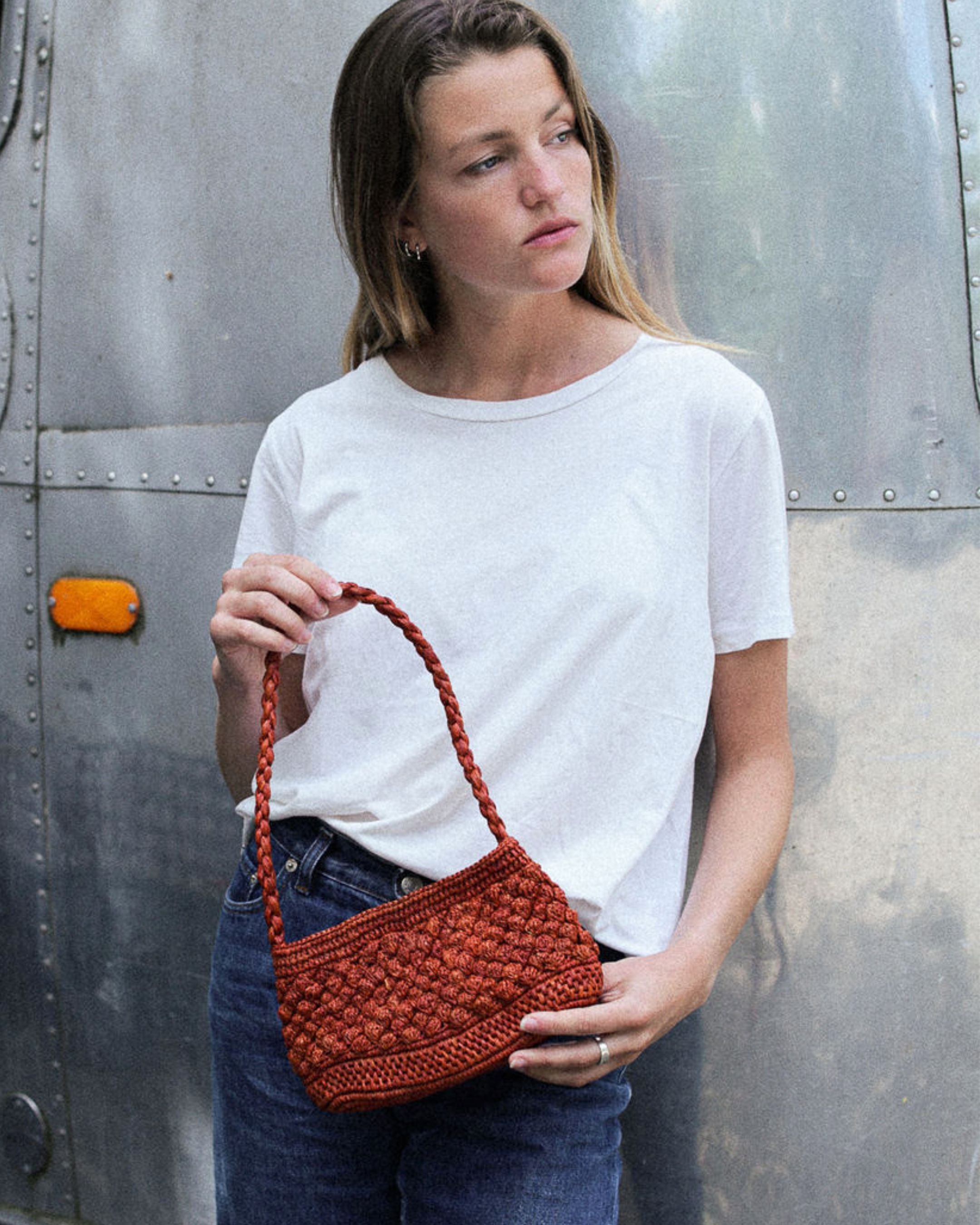 petit sac baguette terracotta en raphia boules porté sur un jean 