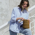 petit sac seau en crochet de raphia vert automne posé sur la jambe