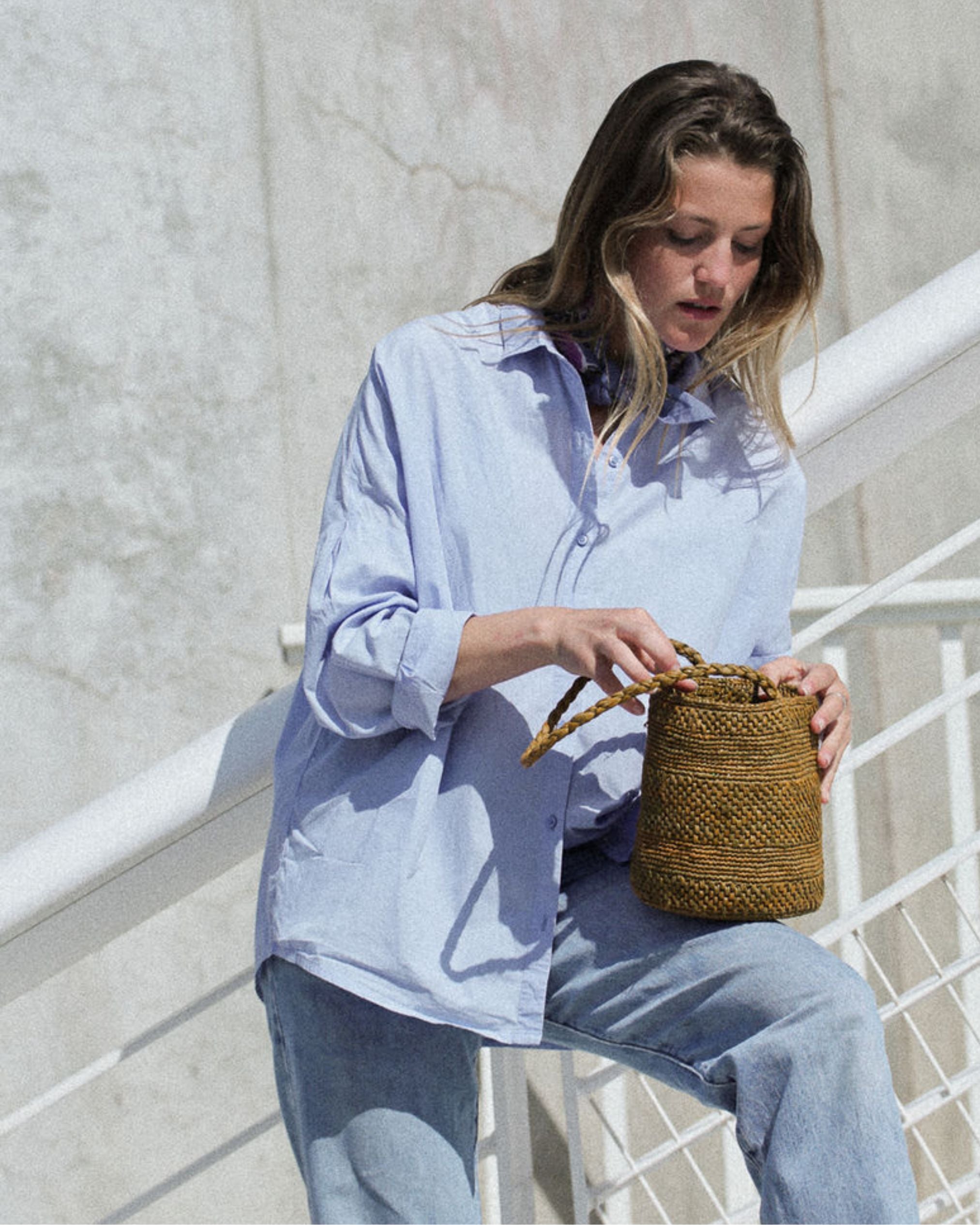 petit sac seau en crochet de raphia vert automne posé sur la jambe