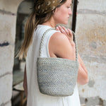 zoom sur le petit sac seau en raphia bleu écume porté avec une robe