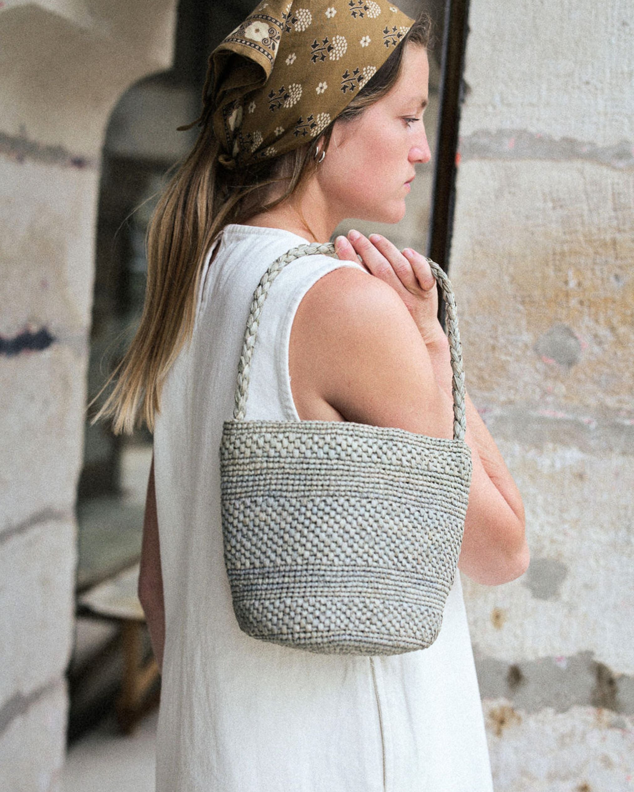 zoom sur le petit sac seau en raphia bleu écume porté avec une robe