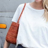 zoom sur le petit sac seau en raphia sienne porté à l'épaule