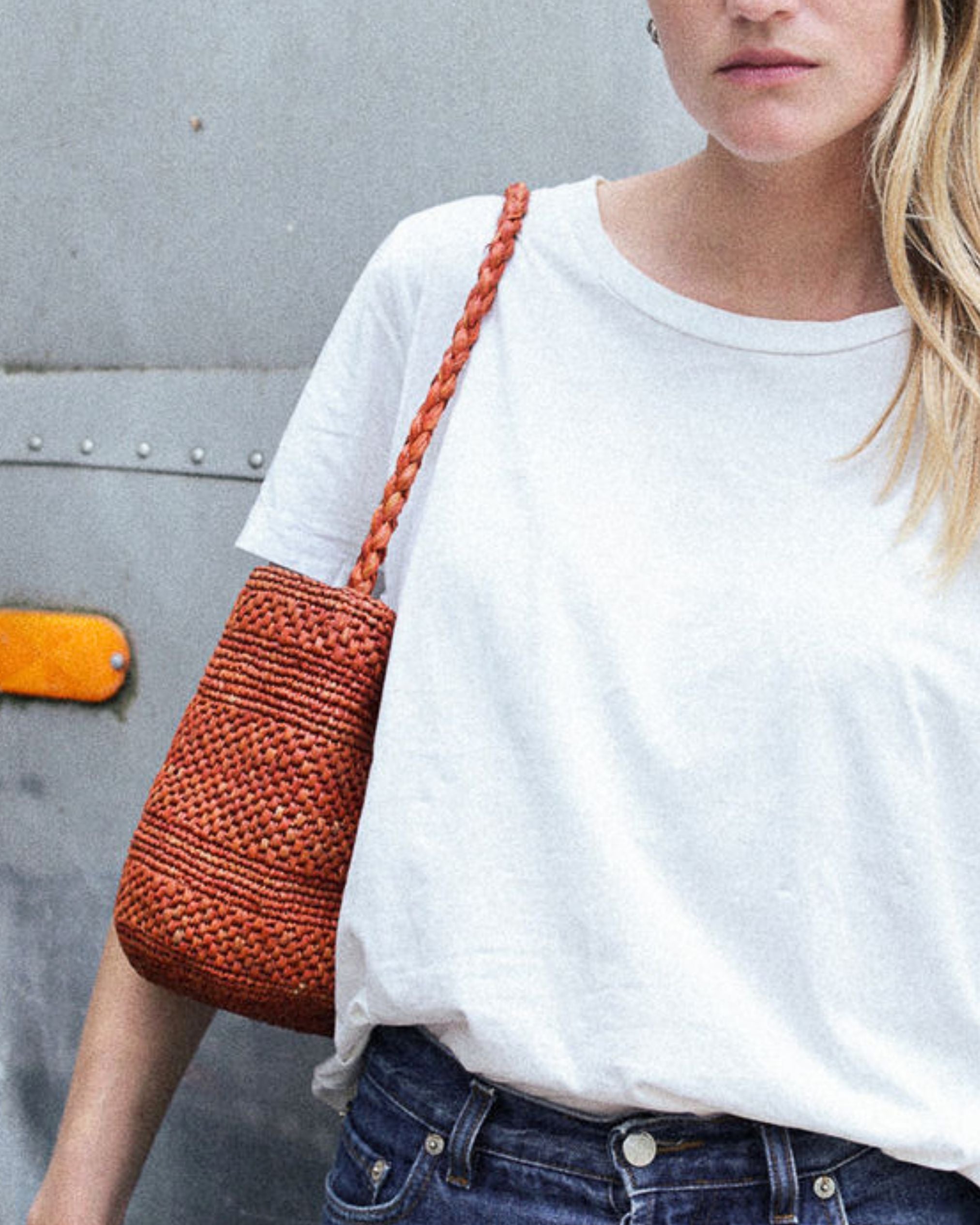 zoom sur le petit sac seau en raphia sienne porté à l'épaule