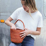 petit sac seau en raphia terracotta porté avec une tenue de ville