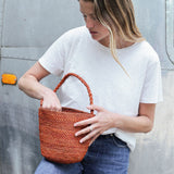 petit sac seau en raphia terracotta porté avec une tenue de ville