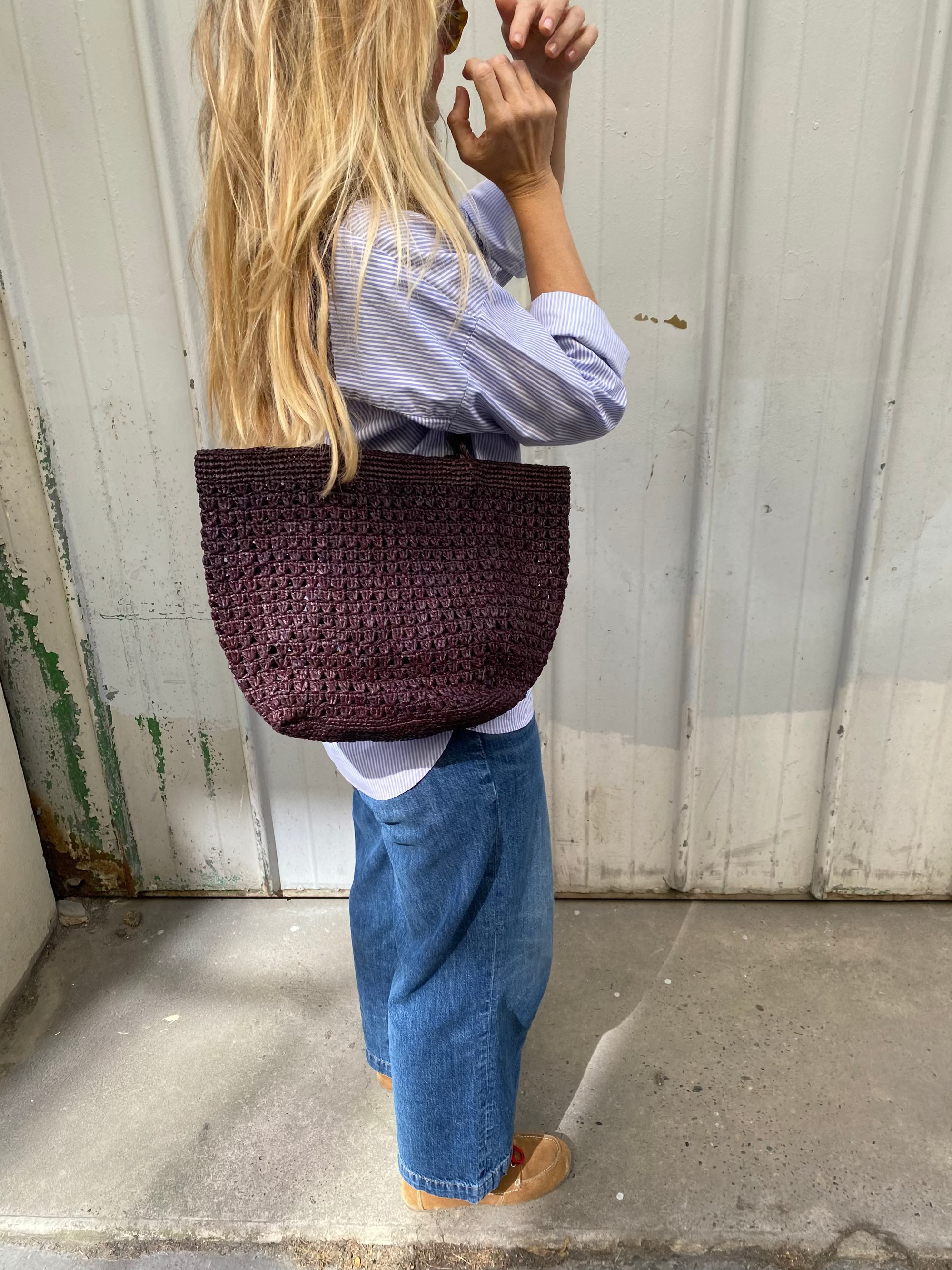 sac cabas ajouré en raphia chocolat porté à l'épaule avec une tenue décontractée