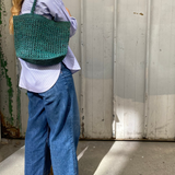 sac cabas ajouré en raphia vert porté à l'épaule 