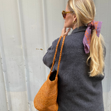 vue de profil du sac seau en raphia cannelle porté avec une tenue automnale